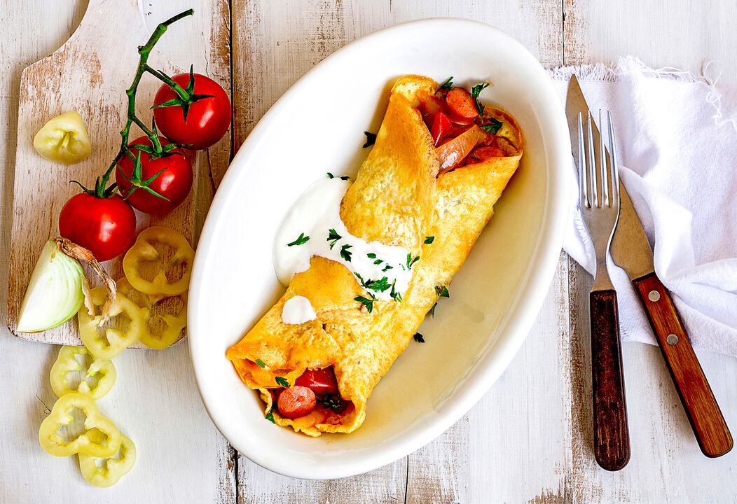 Pusryčiams keto dietos metantys svorį valgo omletą su sūriu, daržovėmis ir kumpiu